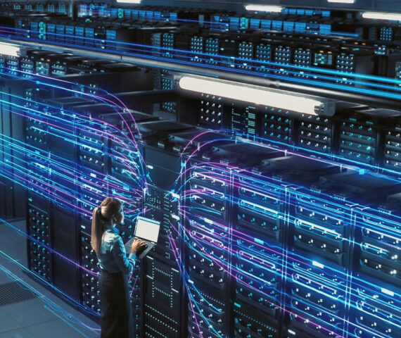 Data technician standing in front of multiple rows of servers