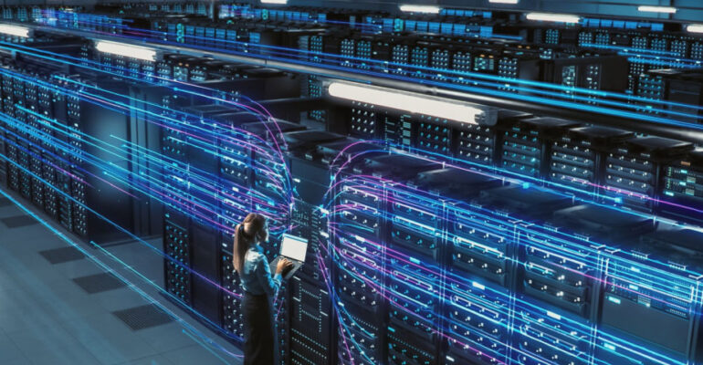 Data technician standing in front of multiple rows of servers