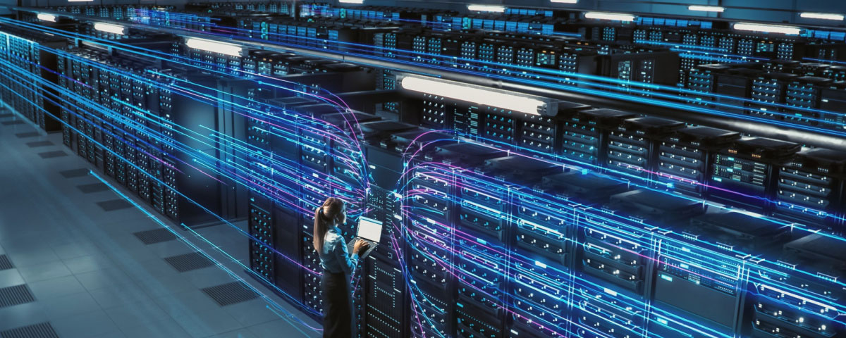 Data technician standing in front of multiple rows of servers