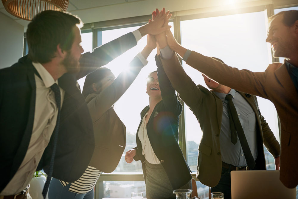 Group of business people in a circle with their hands raised to come together