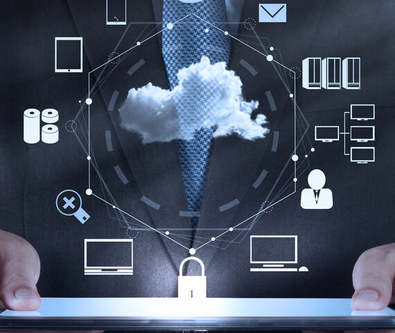 Man in suite holding laptop with cloud and computer icons floating above it