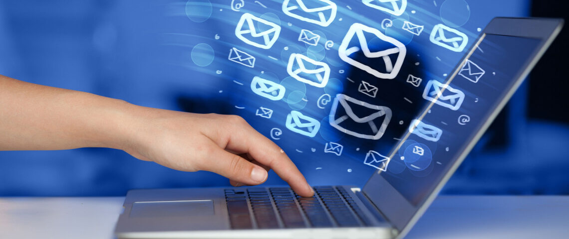 Hand touching a laptop with email icons streaming out of the screen