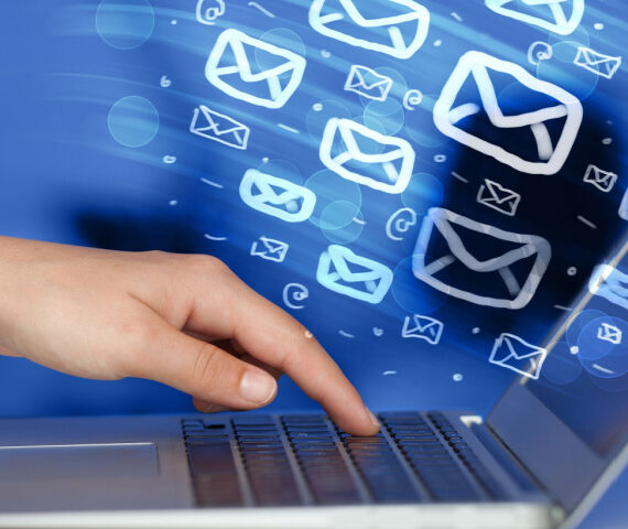 Hand touching a laptop with email icons streaming out of the screen