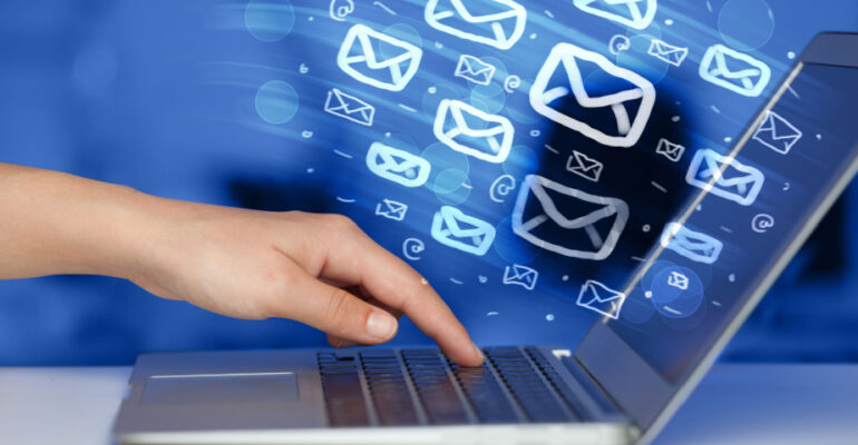 Hand touching a laptop with email icons streaming out of the screen