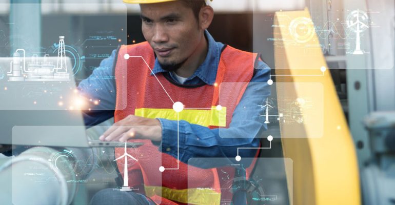 Engineer in factory on laptop using AI for maintenance tasks