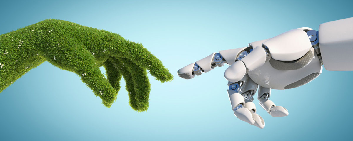 Hand covered in green grass with finger extended to touch finger of robotic hand