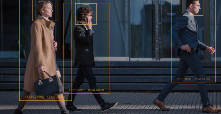People walking on a sidewalk with tracking technology frames around them