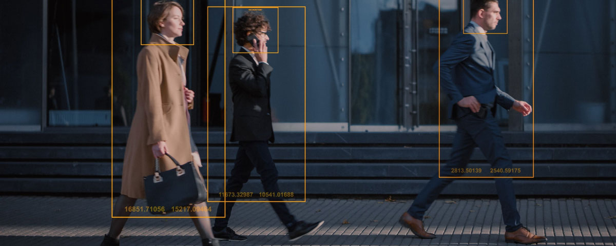 People walking on a sidewalk with tracking technology frames around them